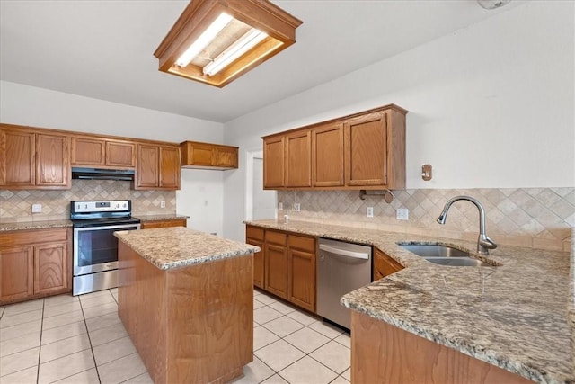 kitchen featuring backsplash, sink, light stone countertops, a kitchen island, and stainless steel appliances