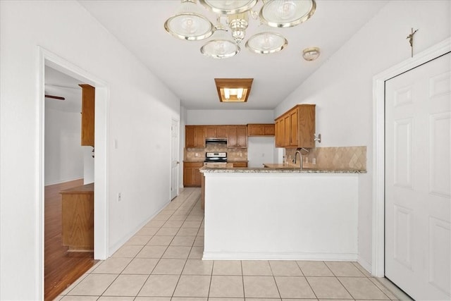 kitchen featuring backsplash, light stone counters, light tile patterned floors, white refrigerator, and stainless steel range with electric cooktop