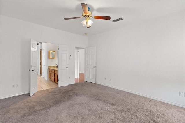 unfurnished bedroom with ensuite bathroom, ceiling fan, and light colored carpet