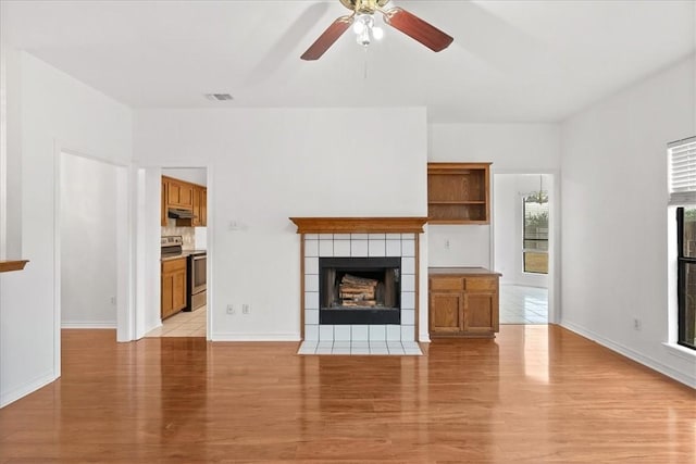 unfurnished living room with a tile fireplace, light hardwood / wood-style flooring, and ceiling fan