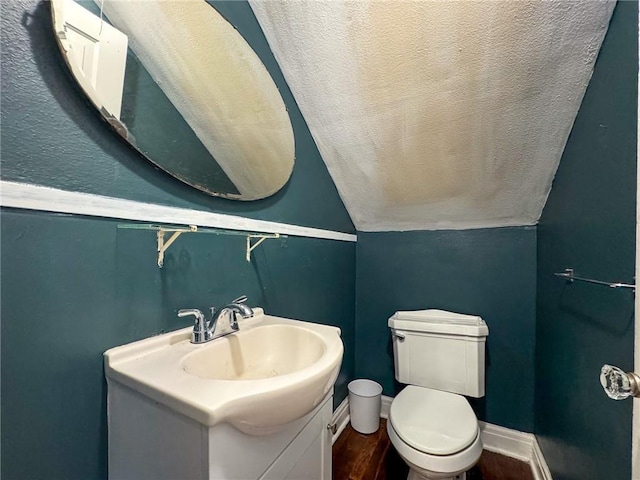 bathroom featuring hardwood / wood-style floors, vanity, toilet, and lofted ceiling