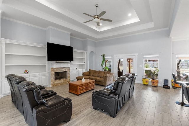 living room with french doors, ornamental molding, a raised ceiling, built in features, and a fireplace