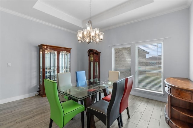 dining room with a tray ceiling, light hardwood / wood-style flooring, ornamental molding, and a chandelier