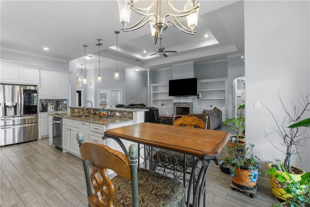 kitchen with pendant lighting, white cabinetry, stainless steel appliances, a tray ceiling, and light stone countertops