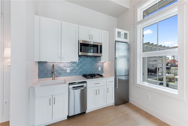 kitchen with white cabinets, a wealth of natural light, stainless steel appliances, and light hardwood / wood-style floors