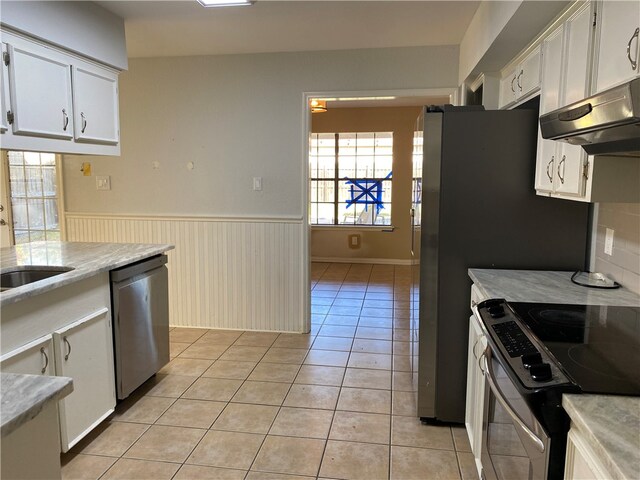 kitchen featuring light tile patterned flooring, decorative backsplash, white cabinets, and stainless steel appliances