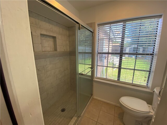 bathroom featuring toilet, tile patterned floors, and a shower with shower door