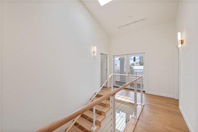 416 E Ave C Ave, Port Aransas, TX 78373 - hallway with an upstairs landing, rail lighting, baseboards, light wood finished floors, and french doors