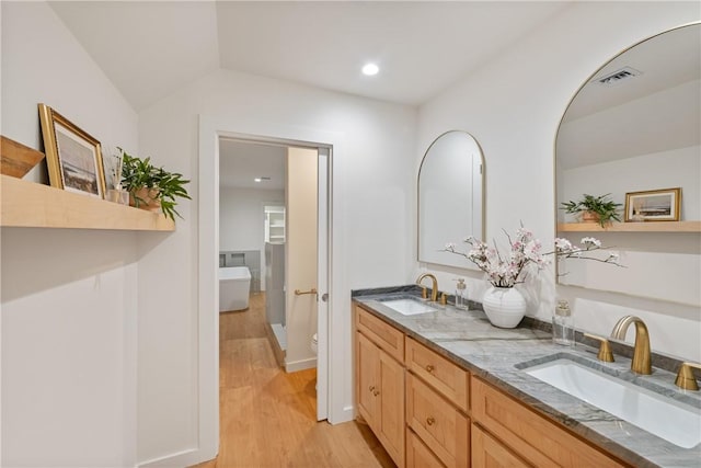 416 E Ave C Ave, Port Aransas, TX 78373 - bathroom featuring double vanity, wood finished floors, recessed lighting, toilet, and a soaking tub