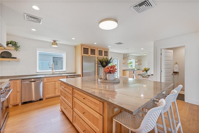 416 E Ave C Ave, Port Aransas, TX 78373 - kitchen featuring stainless steel appliances, open shelves, a sink, a breakfast bar area, and light wood-style flooring