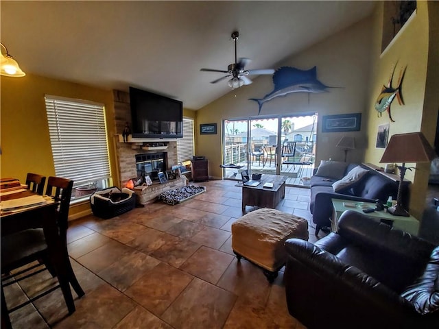 living area featuring a ceiling fan, vaulted ceiling, and a large fireplace