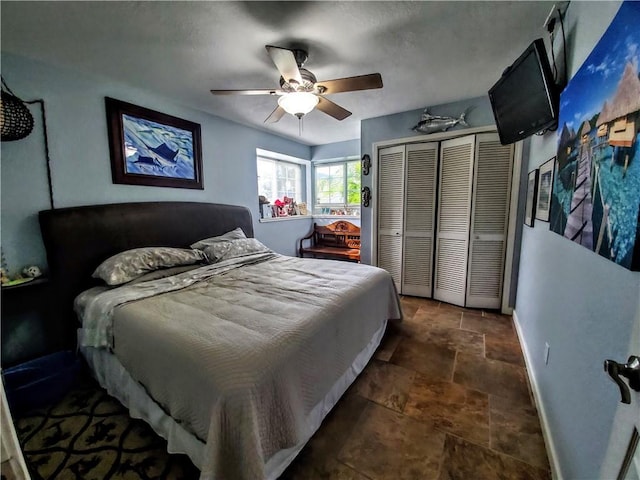 bedroom featuring stone finish flooring, baseboards, a closet, and a ceiling fan