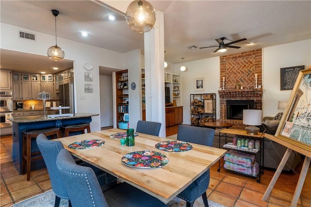 dining room with ceiling fan, a fireplace, and a textured ceiling