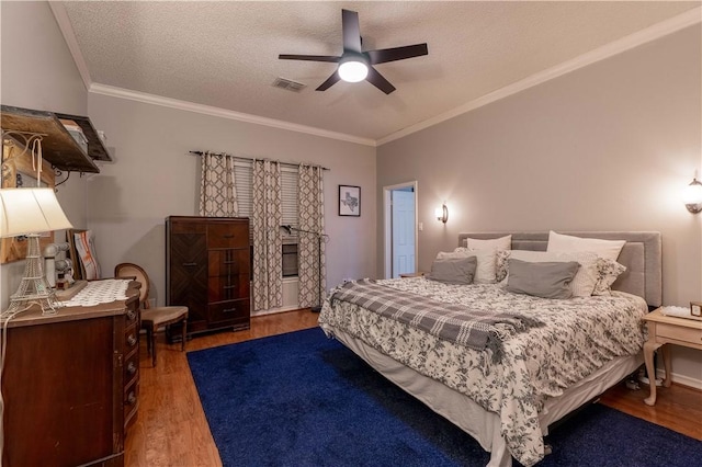 bedroom with ceiling fan, ornamental molding, wood-type flooring, and a textured ceiling