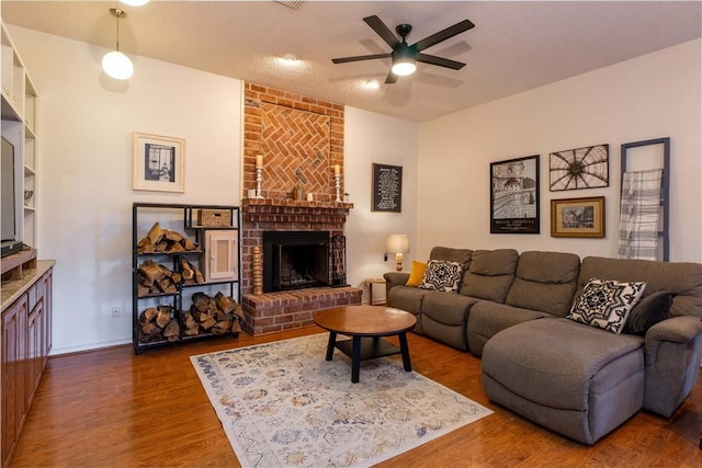 living room featuring dark wood-type flooring, ceiling fan, and a fireplace