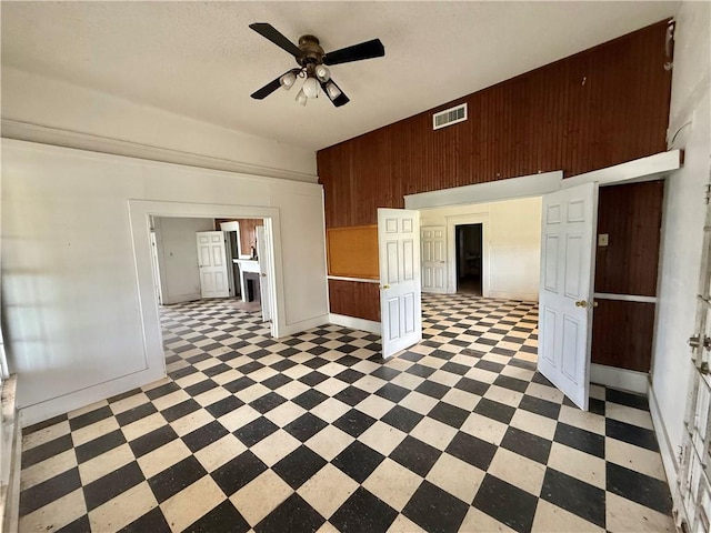 spare room with wooden walls, ceiling fan, visible vents, and light floors