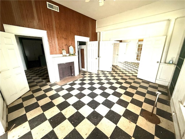 unfurnished living room featuring wooden walls, tile patterned floors, visible vents, and a fireplace