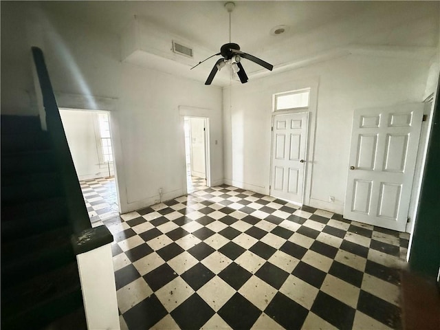 interior space with visible vents, baseboards, a raised ceiling, tile patterned floors, and a ceiling fan