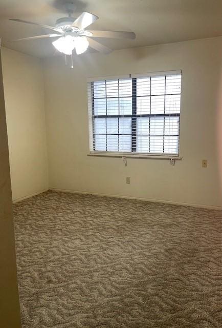 spare room with ceiling fan and dark carpet