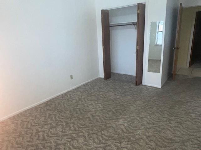 unfurnished bedroom featuring dark carpet and a closet