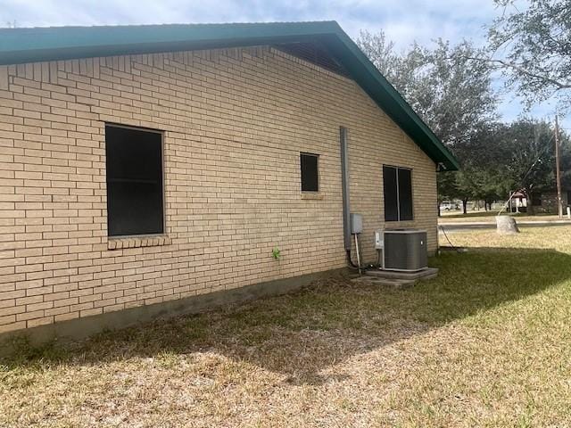 view of side of property with central AC unit and a lawn