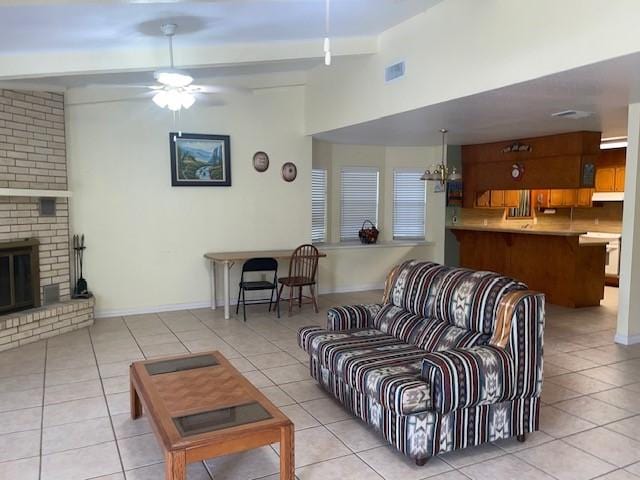 tiled living room featuring a fireplace and ceiling fan