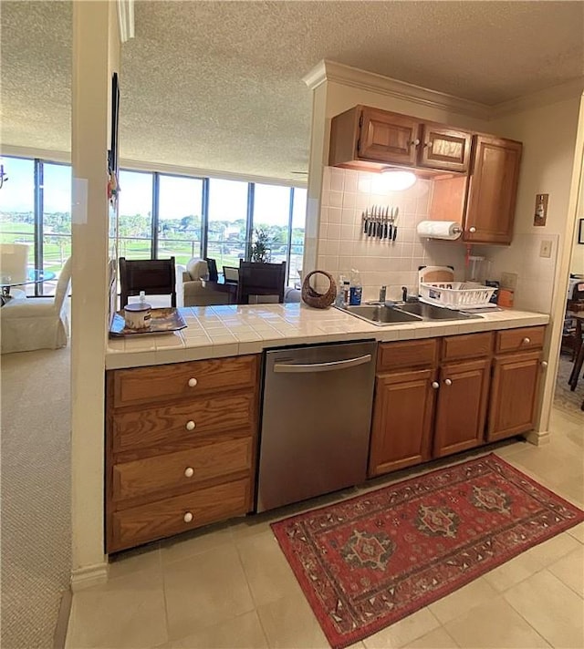 1400 Ocean Dr Unit 503-C, Corpus Christi, TX 78404 - kitchen with dishwasher, brown cabinets, a textured ceiling, healthy amount of natural light, and light tile patterned flooring