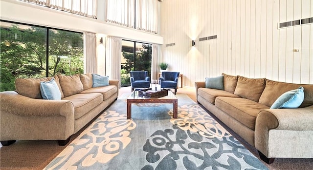 carpeted living room with a high ceiling and wooden walls