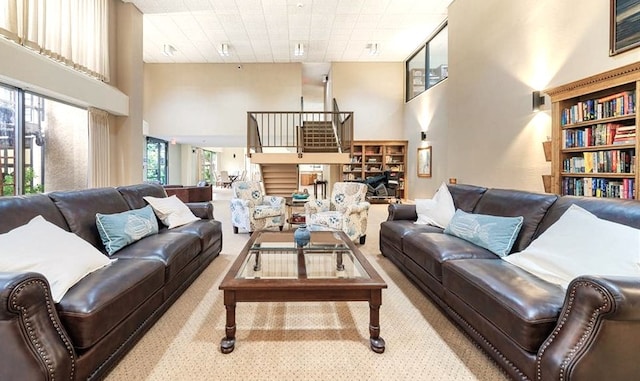 living room with a wealth of natural light, light carpet, and a towering ceiling