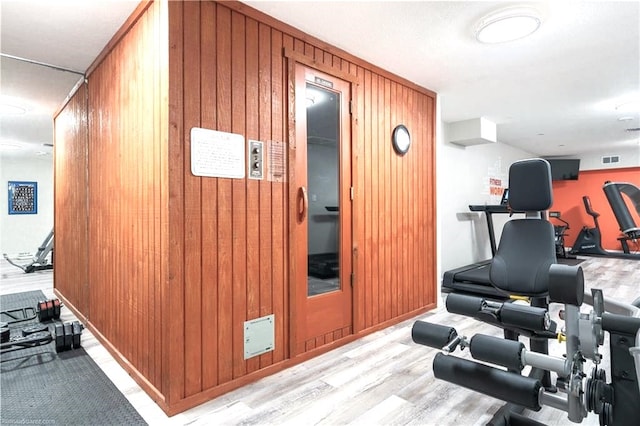 workout area featuring wood walls and light wood-type flooring