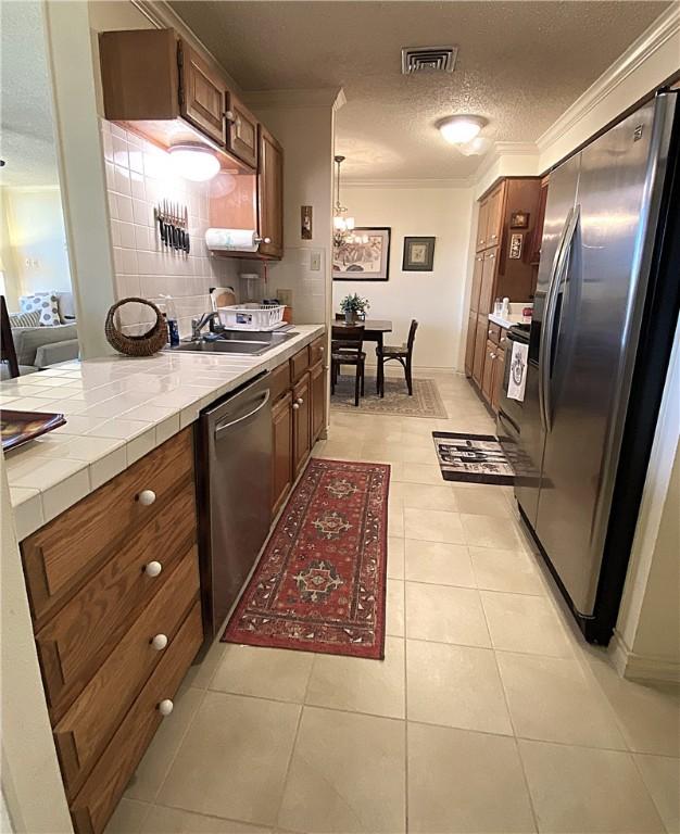 1400 Ocean Dr Unit 503-C, Corpus Christi, TX 78404 - kitchen with appliances with stainless steel finishes, crown molding, tile countertops, a textured ceiling, and light tile patterned floors