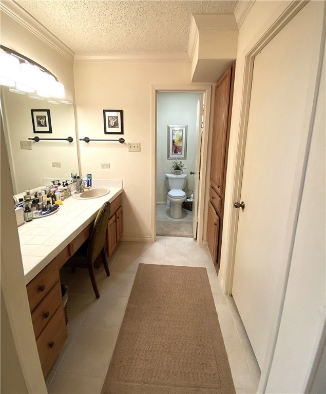 bathroom with tile patterned floors, toilet, a textured ceiling, ornamental molding, and vanity