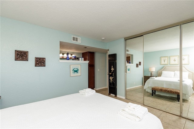 tiled bedroom with a closet and a textured ceiling