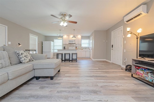 living room featuring light hardwood / wood-style flooring, a wall mounted AC, and ceiling fan