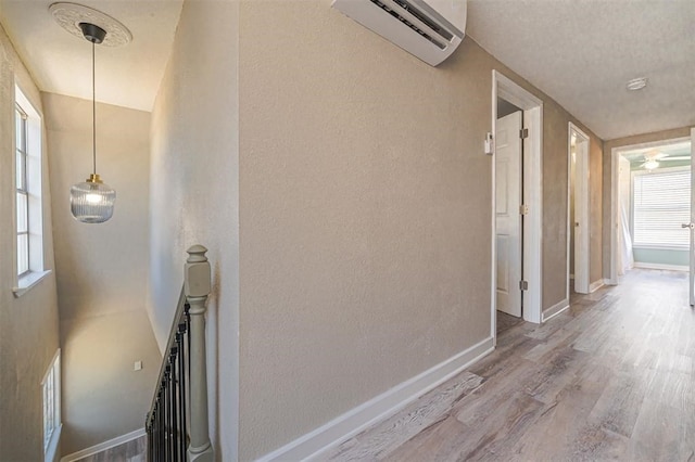 hall featuring a wall mounted air conditioner, a healthy amount of sunlight, and hardwood / wood-style floors