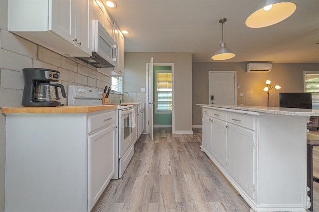 kitchen featuring white cabinetry, a wall unit AC, decorative light fixtures, white appliances, and decorative backsplash