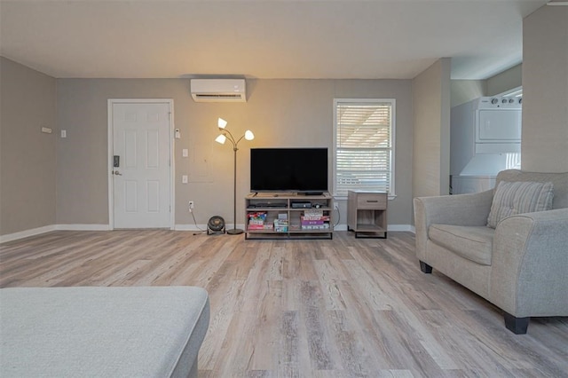living room featuring an AC wall unit, stacked washer and dryer, and light hardwood / wood-style flooring