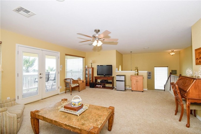 living area featuring french doors, visible vents, and light colored carpet