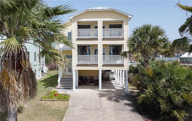 coastal inspired home with a carport, stairway, and driveway