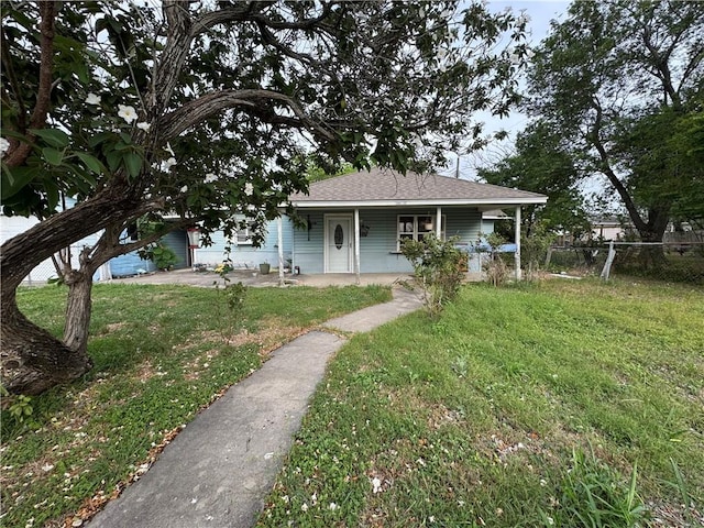 view of front of home with fence, covered porch, a front yard, and roof with shingles