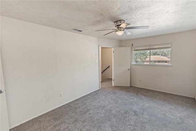 carpeted empty room featuring a ceiling fan, visible vents, and a textured ceiling