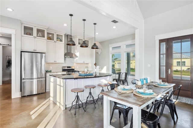 kitchen featuring white cabinetry, appliances with stainless steel finishes, a healthy amount of sunlight, and decorative light fixtures