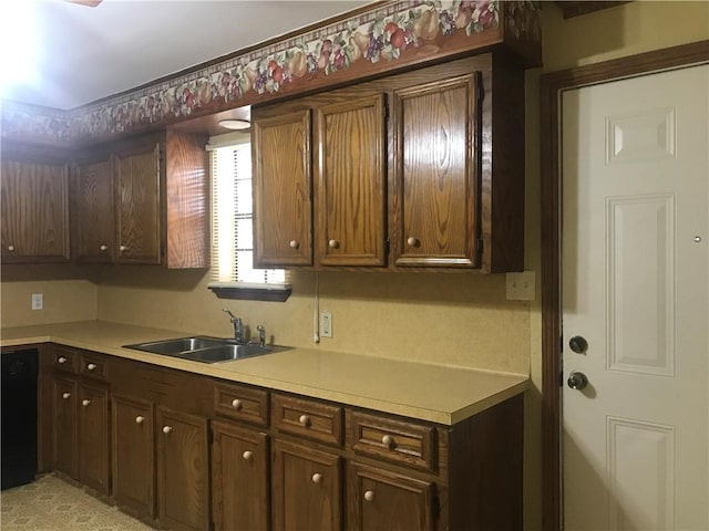 kitchen featuring dark brown cabinetry, sink, and black dishwasher