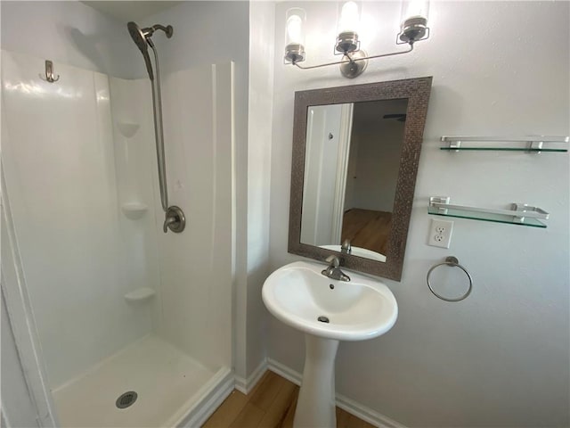 bathroom featuring baseboards, wood finished floors, and a stall shower