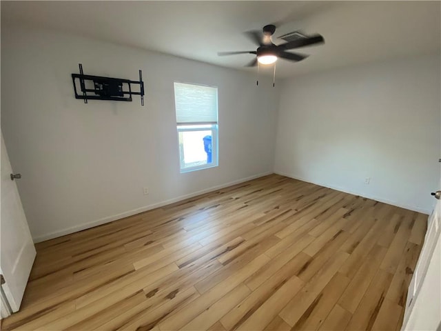 spare room featuring light wood-style floors, baseboards, ceiling fan, and visible vents