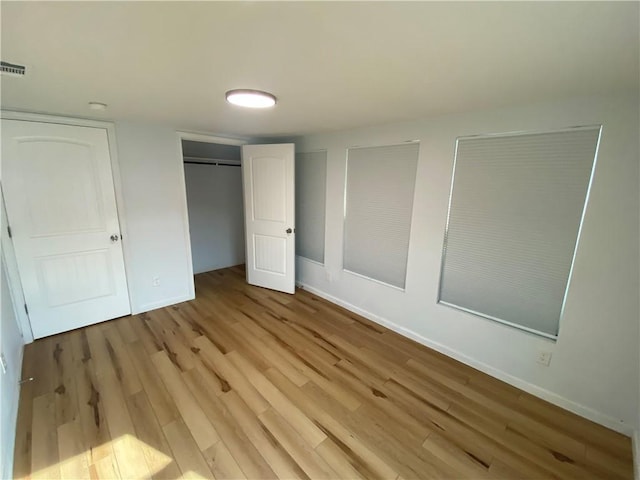 unfurnished bedroom featuring baseboards, a closet, light wood-style flooring, and visible vents