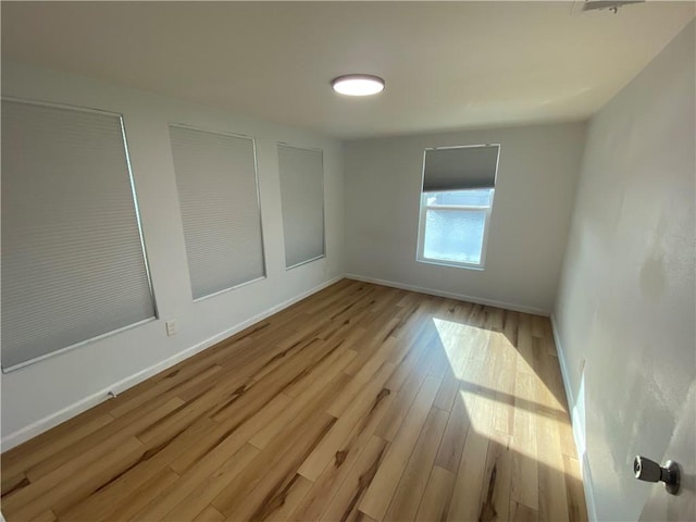unfurnished room with baseboards and light wood finished floors