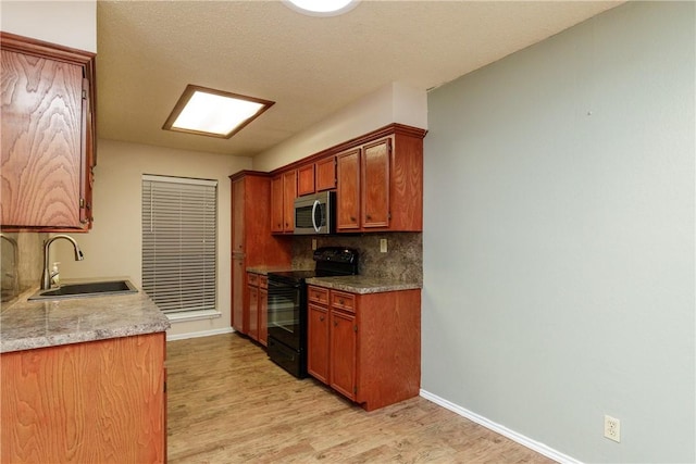 13656 Teague Ln Unit 60, Corpus Christi, TX 78410 - kitchen with black range with electric stovetop, stainless steel microwave, a sink, light wood-style flooring, and baseboards