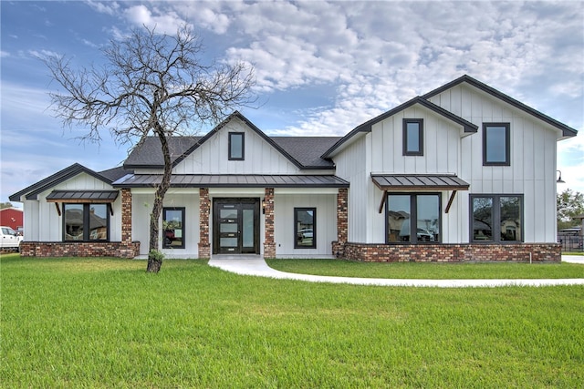 modern farmhouse style home featuring a standing seam roof, a front lawn, board and batten siding, and brick siding