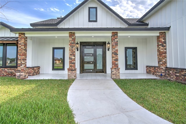 entrance to property with a shingled roof, board and batten siding, and a lawn